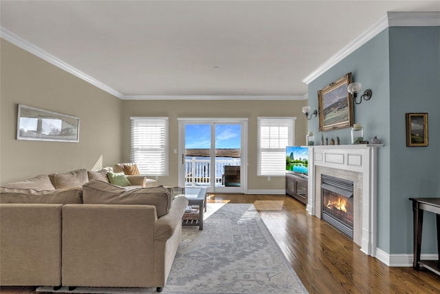 living area with plenty of natural light, crown molding, a tiled fireplace, and wood finished floors