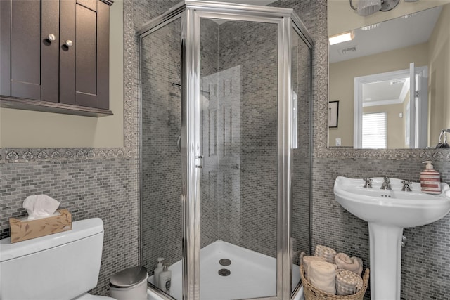 bathroom with toilet, visible vents, tile walls, wainscoting, and a shower stall