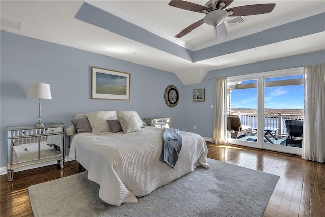 bedroom with visible vents, access to outside, a tray ceiling, hardwood / wood-style floors, and crown molding