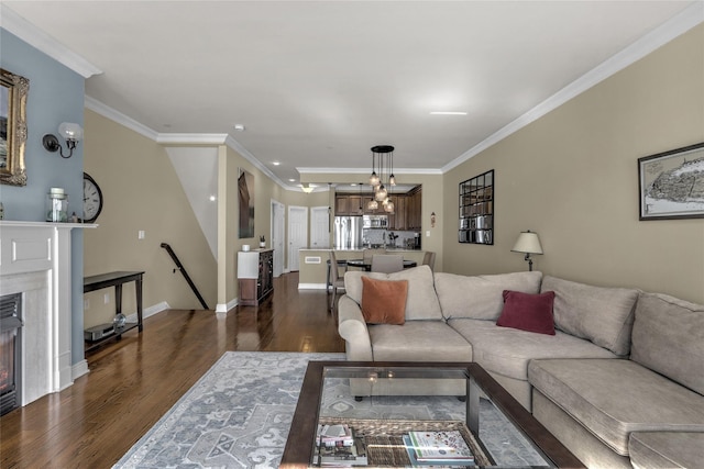 living room featuring dark wood-style floors, a premium fireplace, baseboards, and crown molding