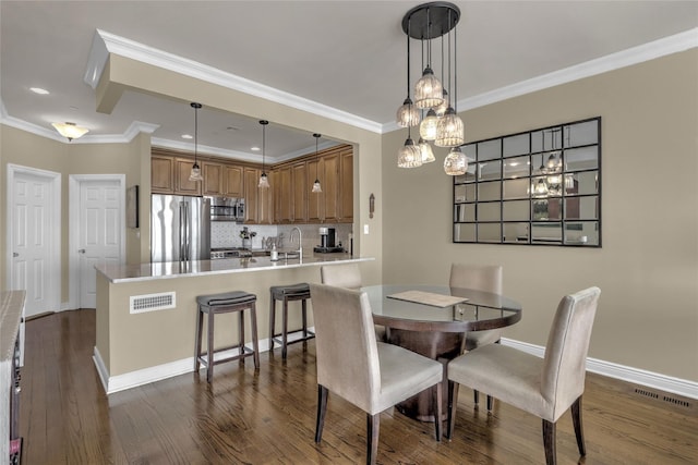 dining room featuring dark wood-style floors, visible vents, crown molding, and baseboards