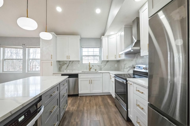 kitchen with decorative backsplash, dark wood-style floors, appliances with stainless steel finishes, wall chimney range hood, and a sink