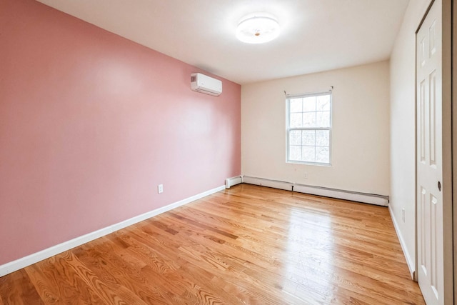 unfurnished bedroom featuring a wall unit AC, light wood finished floors, a closet, baseboard heating, and baseboards