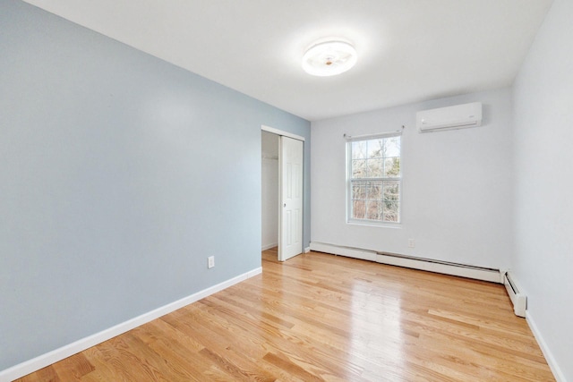 empty room featuring a baseboard radiator, a wall mounted air conditioner, baseboards, and wood finished floors