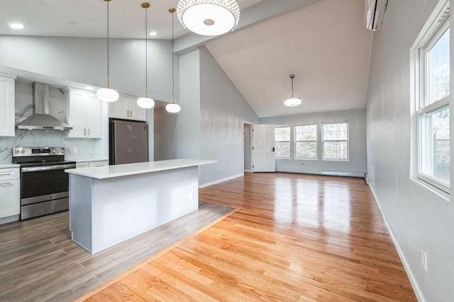 kitchen featuring light wood finished floors, wall chimney exhaust hood, appliances with stainless steel finishes, light countertops, and white cabinetry