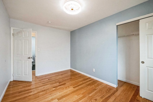 unfurnished bedroom featuring baseboards, a closet, and light wood-style floors