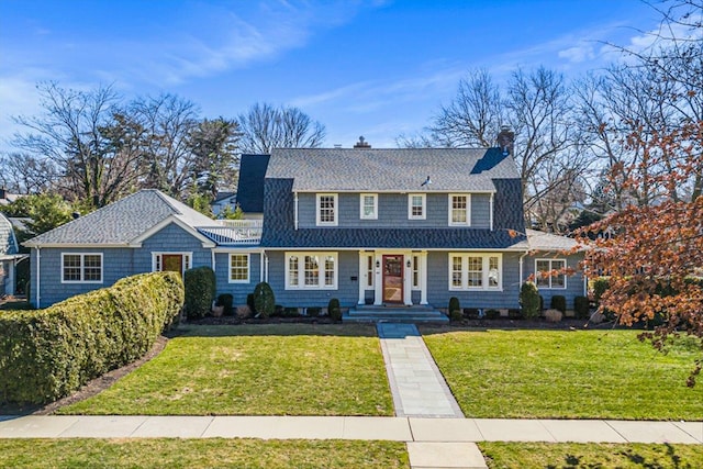 view of front of home featuring a chimney, roof with shingles, and a front lawn