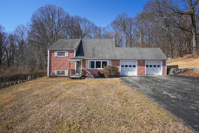 tri-level home featuring an attached garage, a shingled roof, a front lawn, aphalt driveway, and brick siding