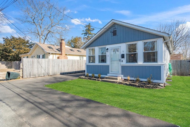 bungalow-style house with fence and a front lawn