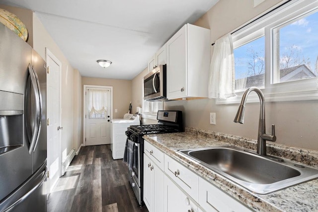 kitchen featuring dark wood-type flooring, a sink, white cabinets, appliances with stainless steel finishes, and washer / clothes dryer