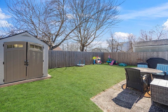 view of yard with a fenced backyard, a storage unit, a patio, and an outbuilding