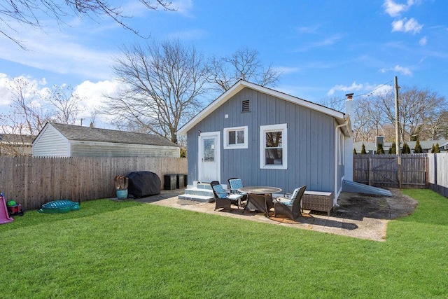 rear view of property with entry steps, a fenced backyard, a yard, and an outbuilding