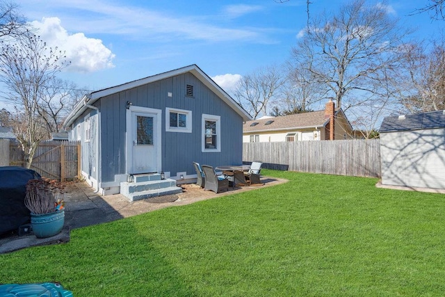 back of property with an outbuilding, a lawn, a fenced backyard, and entry steps