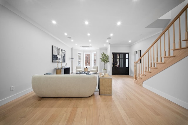 living area with stairs, crown molding, light wood-style floors, and baseboards