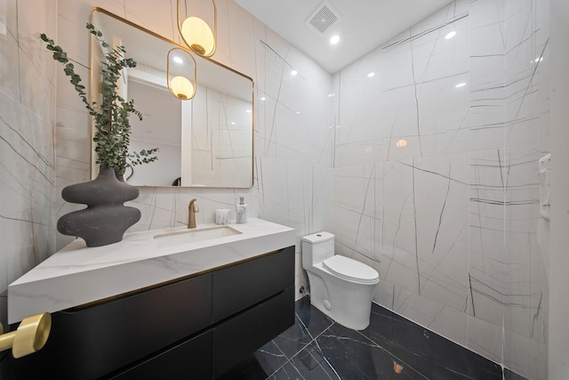 bathroom with visible vents, toilet, marble finish floor, tile walls, and vanity