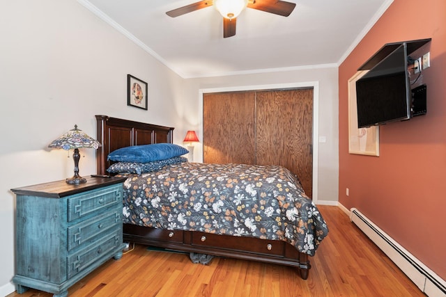 bedroom with crown molding, baseboard heating, a ceiling fan, wood finished floors, and baseboards