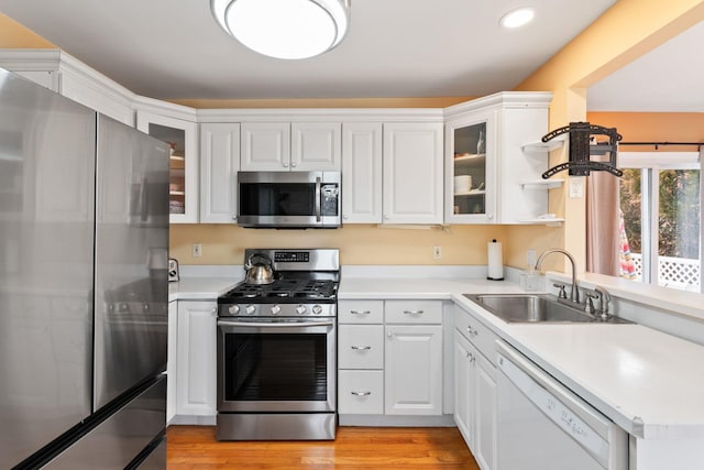 kitchen with appliances with stainless steel finishes, light countertops, a sink, and a peninsula