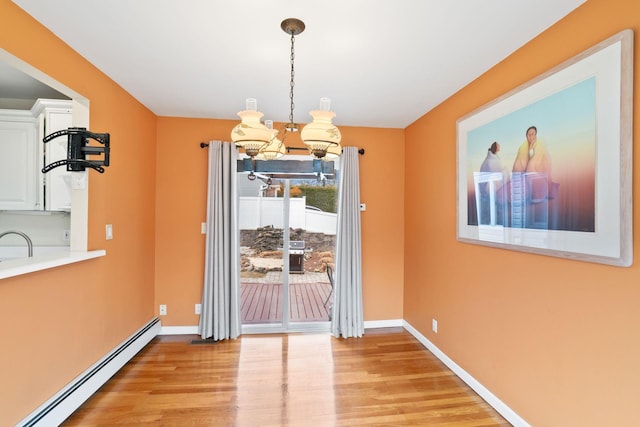 dining area featuring light wood-type flooring, a baseboard radiator, and baseboards