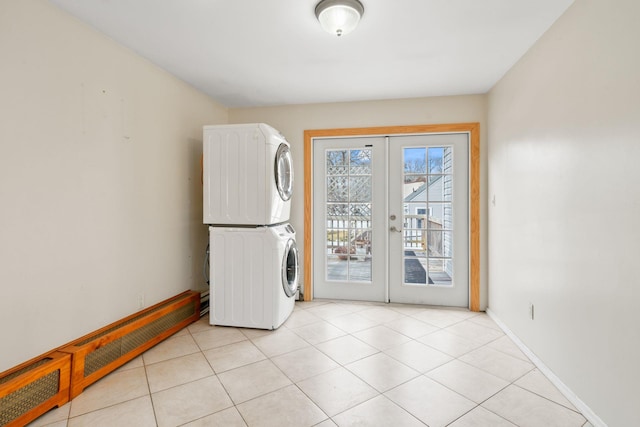 washroom featuring french doors, light tile patterned floors, stacked washing maching and dryer, laundry area, and baseboards