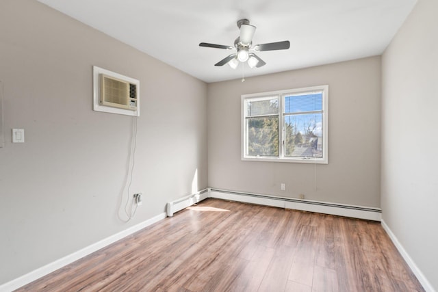 spare room featuring a wall mounted AC, a baseboard heating unit, ceiling fan, wood finished floors, and baseboards