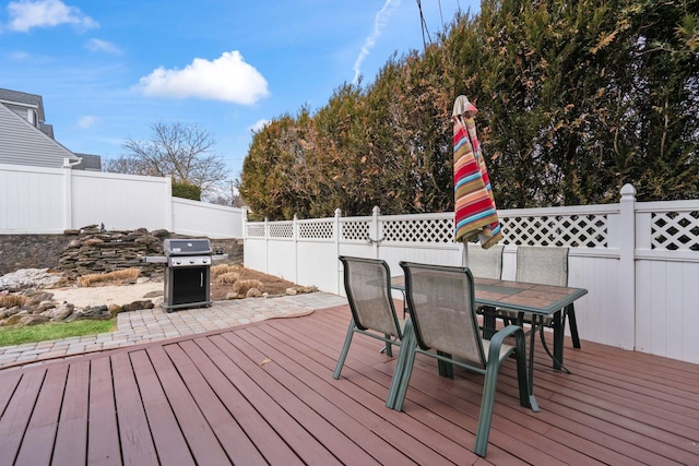 deck with outdoor dining space, area for grilling, and fence