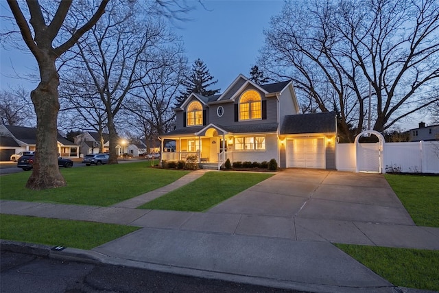 view of front of house featuring a garage, concrete driveway, a gate, fence, and a front yard