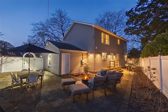 rear view of property featuring a gate, a patio, a fire pit, and fence