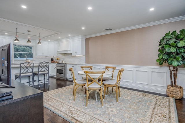 dining area with dark wood-type flooring, wainscoting, visible vents, and crown molding