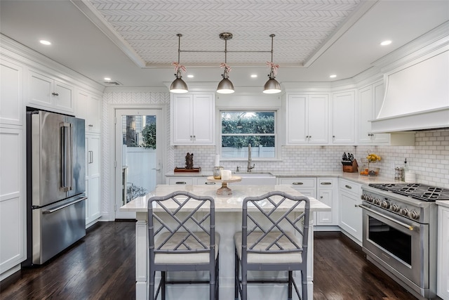 kitchen with premium appliances, a breakfast bar, white cabinets, and a sink