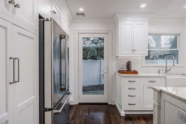 kitchen with visible vents, light stone counters, ornamental molding, freestanding refrigerator, and a sink