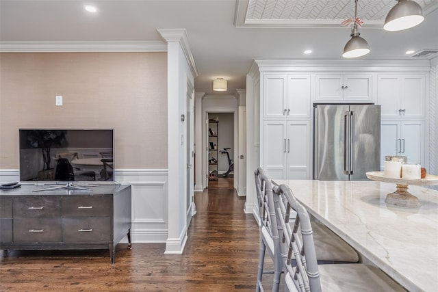 kitchen featuring dark wood-style flooring, white cabinetry, high end fridge, ornamental molding, and light stone countertops