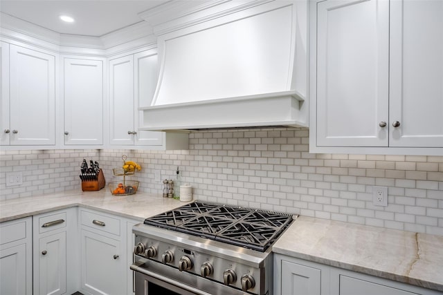 kitchen featuring light stone counters, custom range hood, decorative backsplash, white cabinetry, and gas range