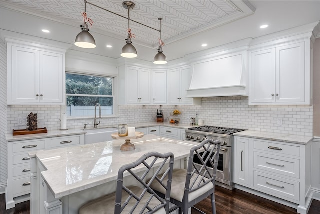 kitchen featuring dark wood finished floors, custom exhaust hood, white cabinets, high end stove, and a kitchen breakfast bar