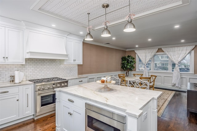 kitchen featuring dark wood-style flooring, crown molding, stainless steel appliances, white cabinets, and premium range hood