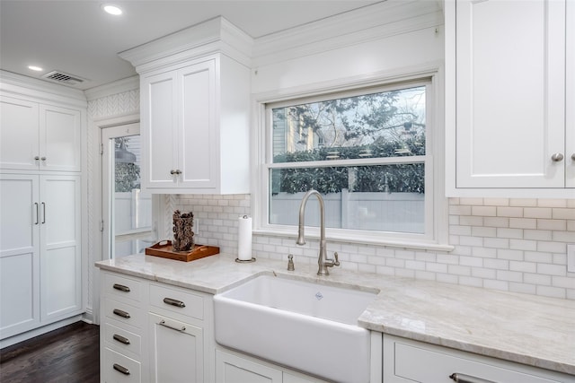 kitchen featuring dark wood-style floors, visible vents, decorative backsplash, white cabinets, and a sink