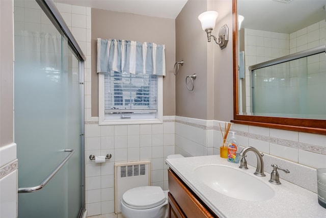 full bathroom with toilet, vanity, tile walls, a stall shower, and radiator heating unit