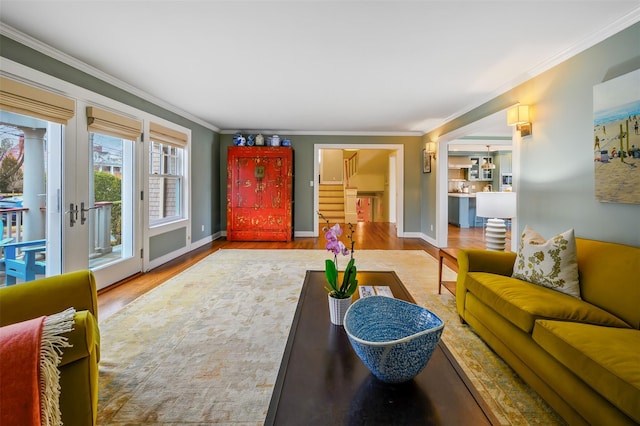 living room with crown molding, stairway, baseboards, and wood finished floors