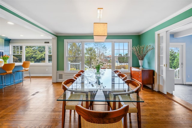 dining space with a wealth of natural light, baseboards, ornamental molding, and wood finished floors