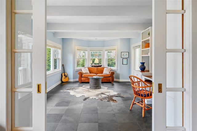 sitting room featuring baseboards and beam ceiling