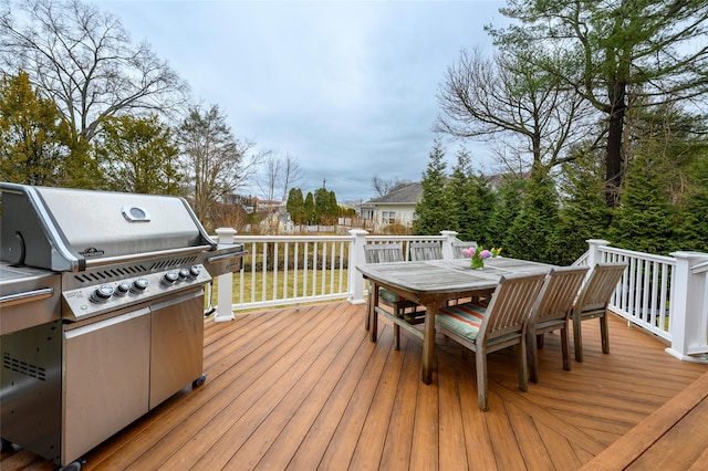 wooden terrace with a grill, fence, and outdoor dining area