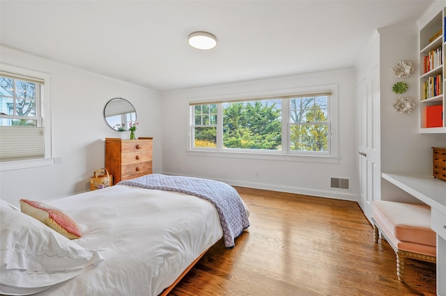 bedroom with visible vents, baseboards, and wood finished floors