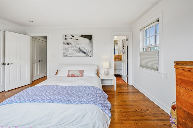 bedroom featuring baseboards, wood finished floors, and crown molding