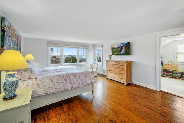 bedroom featuring multiple windows, baseboards, and wood finished floors