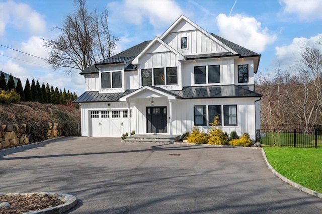 modern inspired farmhouse featuring board and batten siding, a standing seam roof, fence, and an attached garage