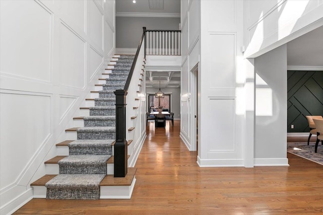 foyer with ornamental molding, light wood-style floors, stairway, and a decorative wall