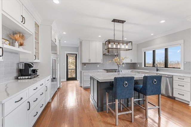 kitchen with white cabinets, ornamental molding, and stainless steel appliances