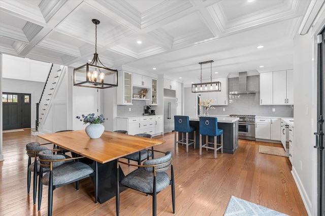 dining area featuring light wood-style floors, beam ceiling, a notable chandelier, and stairway