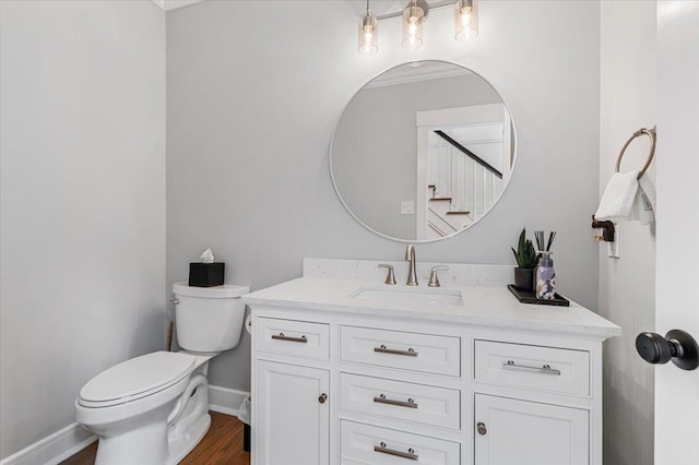 bathroom featuring toilet, baseboards, wood finished floors, and vanity