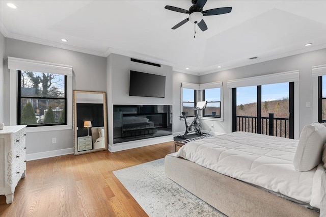 bedroom with crown molding, light wood-type flooring, a glass covered fireplace, and access to exterior