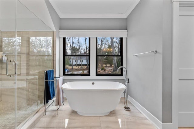 bathroom featuring a stall shower, baseboards, ornamental molding, and a freestanding bath